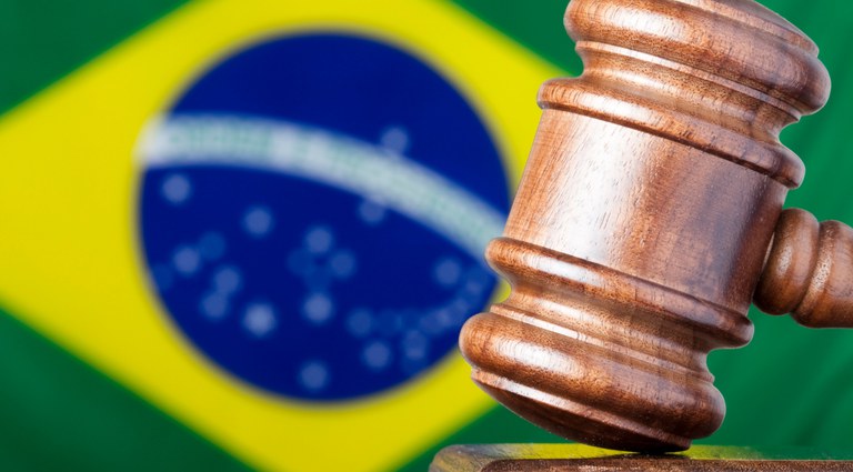 Imagem com uma bandeira do Brasil e um martelo usado por juízes e juízas, a qual remete à legislação brasileira