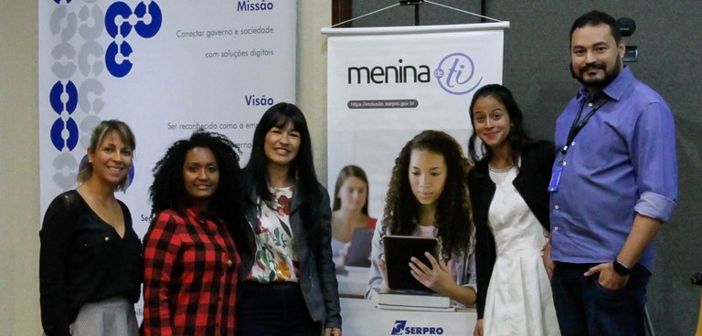 Professores e alunas do Projeto Menina de TI estão lado a lado possando para foto do Menina de TI