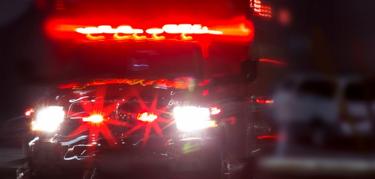 Imagem de uma ambulância em ação na noite de uma cidade grande