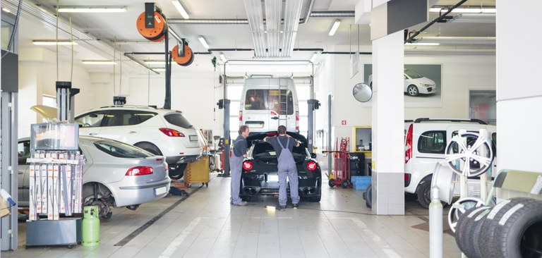 Imagem de mecânicos em uma oficina trabalhando no reparo de um carro