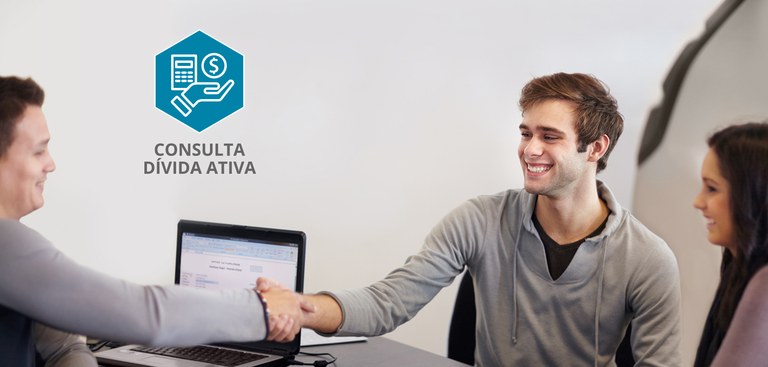 Foto com um casal, de um lado da mesa, e um homem, do outro lado. Na mesa, um computador. Os dois homens sorriem e apertam as mãos. A imagem também traz a logomarca do produto Consulta Dívida Ativa.