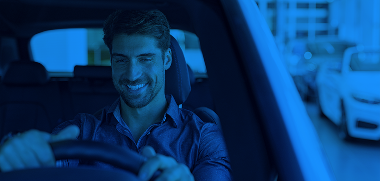 Um homem sorridente dirigindo um carro