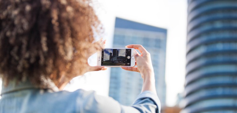 Mulher usa smartphone para tirar foto de prédios altos e espelhados