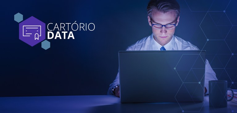 Homem trabalhando em um computador. À esquerda, marca do Cartório Data