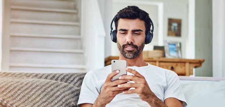 homem-no-sofa-usa-celular-com-fones-de-ouvido.jpg