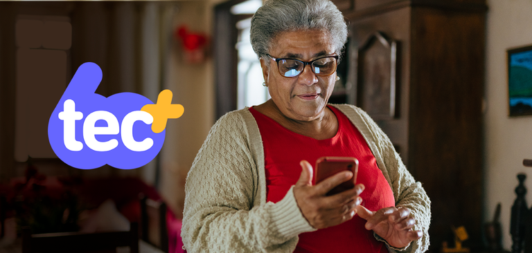 Mulher idosa navega pela internet pelo celular em um ambiente familiar