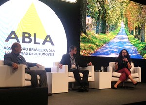 No palco do Fórum da Abla, participam da apresentação, da esquerda para a direita, sentados em poltronas brancas, o diretor de Gestão de Políticas de Trânsito da Senatran, Eduardo Sanches, o secretário Nacional de Trânsito, Frederico Carneiro, e a gerente de Soluções Digitais de Trânsito do Serpro, Patrícia Moraes