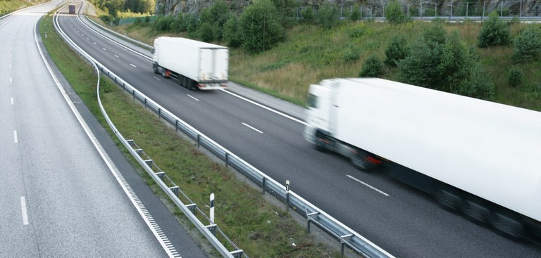 Caminhões trafegando por uma rodovia asfaltada