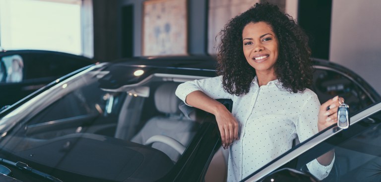 Mulher mostrando a chave do veículo no qual está prestes a entrar