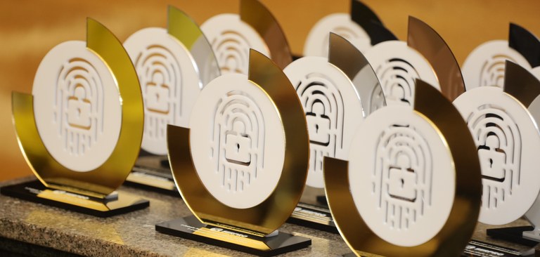 Close na mesa dos troféus entregues aos vencedores do Prêmio Serpro de Privacidade e Proteçãoo de Dados