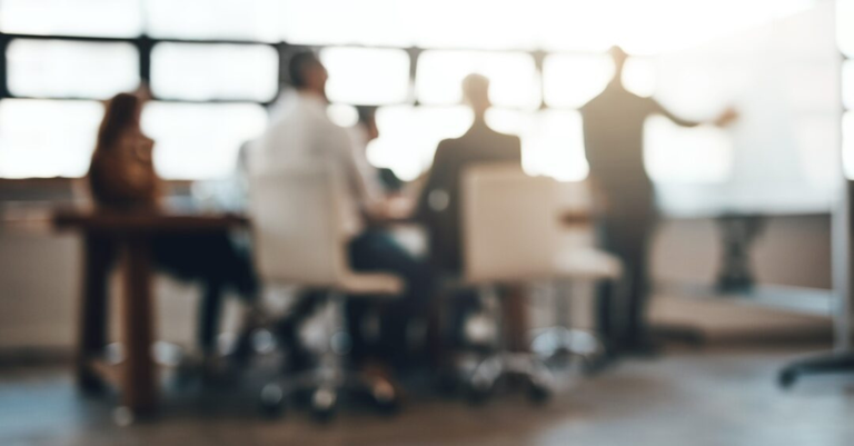 Imagem de uma reunião de trabalho/avaliação. A fotografia está fora de foco para dar um caráter mais estilizado e geral à imagem
