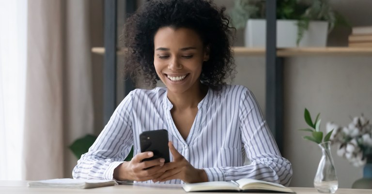 Jovem mulher negra em home office utilizando o celular.jpg