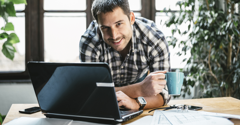 Homem trabalhando no computador em cima de uma mesa