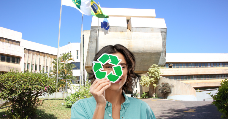 mulher com máscara com ícone de reciclagem em frente à sede do Serpro em Brasília.png