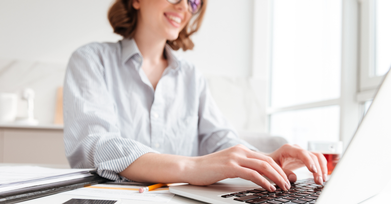Mulher digitando e-mail no computador portátil enquanto está sentada
