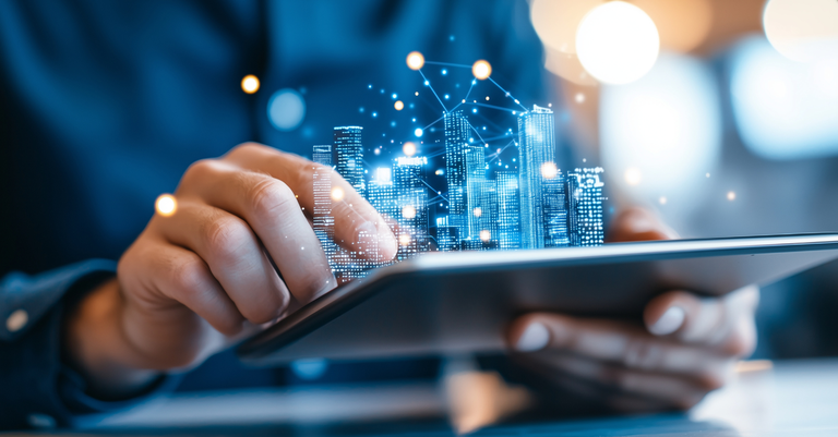 Imagem de uma pessoa operando um tablet do qual se vê projetado o holograma de uma cidade Imagem de uma pessoa operando um tablet do qual se vê projetado o holograma de uma cidade