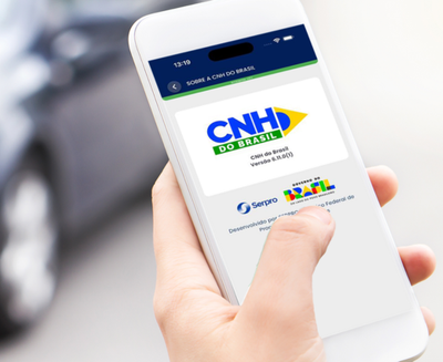 Detalhe de uma mão segurando um celular cuja tela exibe o app CNH do Brasil em funcionamento