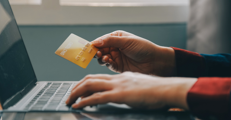 Fotografia de uma pessoa usando um cartão de crédito para fazer um pagamento pela internet em seu laptop Fotografia de uma pessoa usando um cartão de crédito para fazer um pagamento pela internet em seu laptop